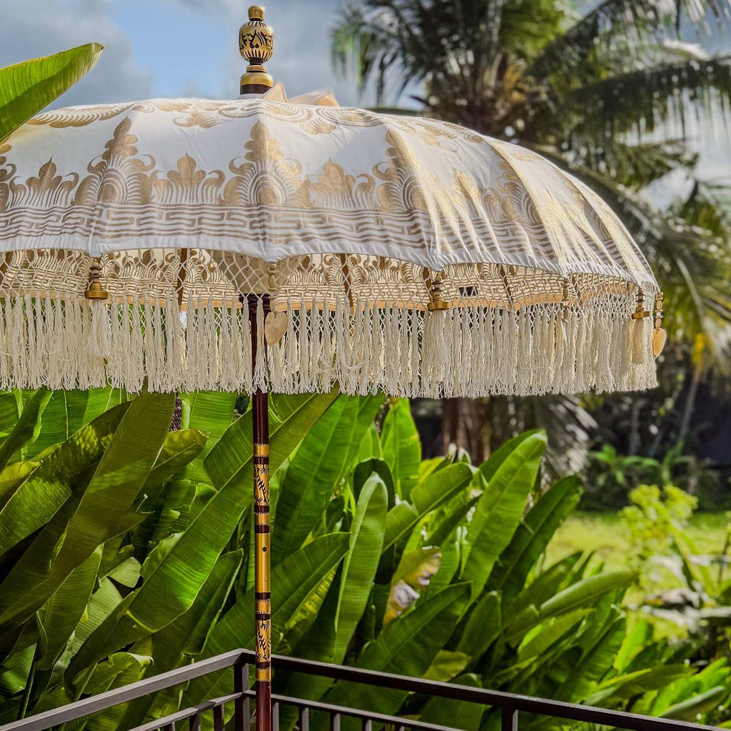 Decorative umbrella with intricate patterns and tassels in a tropical setting