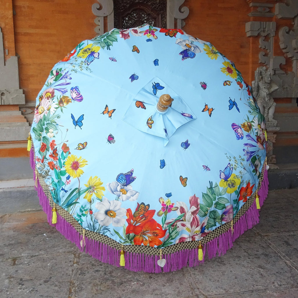 Close-up of the Butterfly Parasol’s canopy, showcasing vibrant floral patterns, blue butterflies, lilac fringe, golden tassels, and mother-of-pearl shell accents.