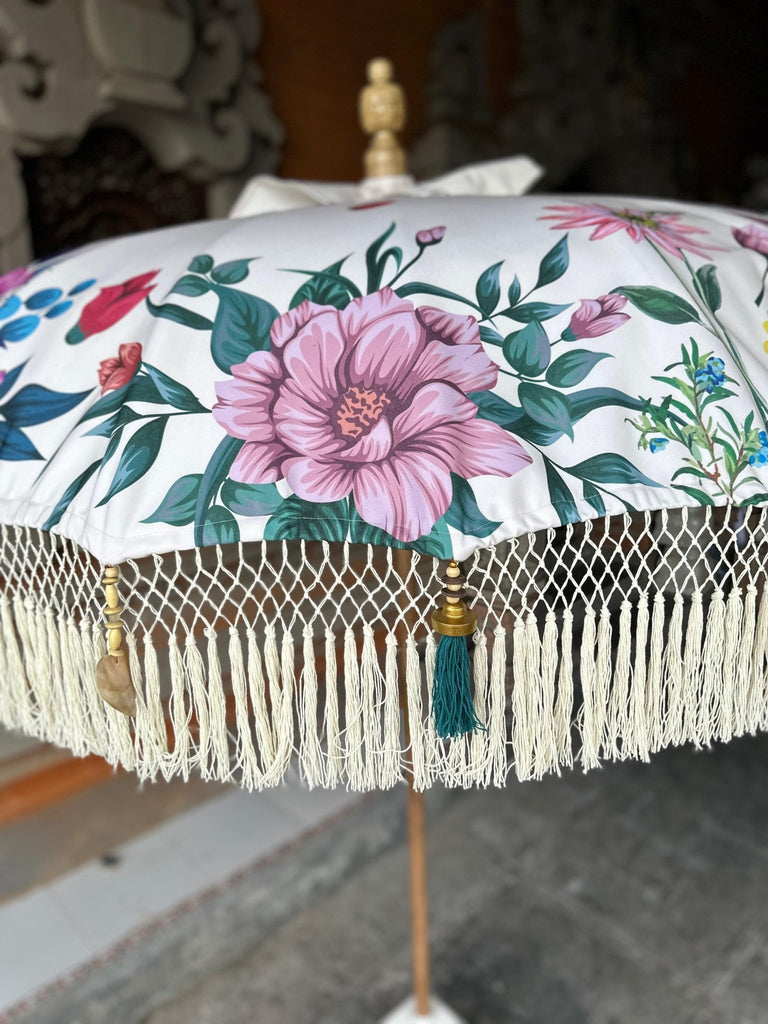 Elegant floral Balinese parasol standing in a traditional Balinese setting, blending vibrant colors and craftsmanship.