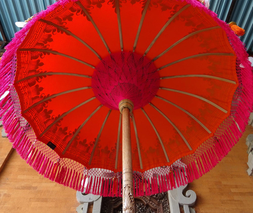 Underside detail of the Clementine Parasol showcasing handcrafted pink macramé fringe and bamboo structure.