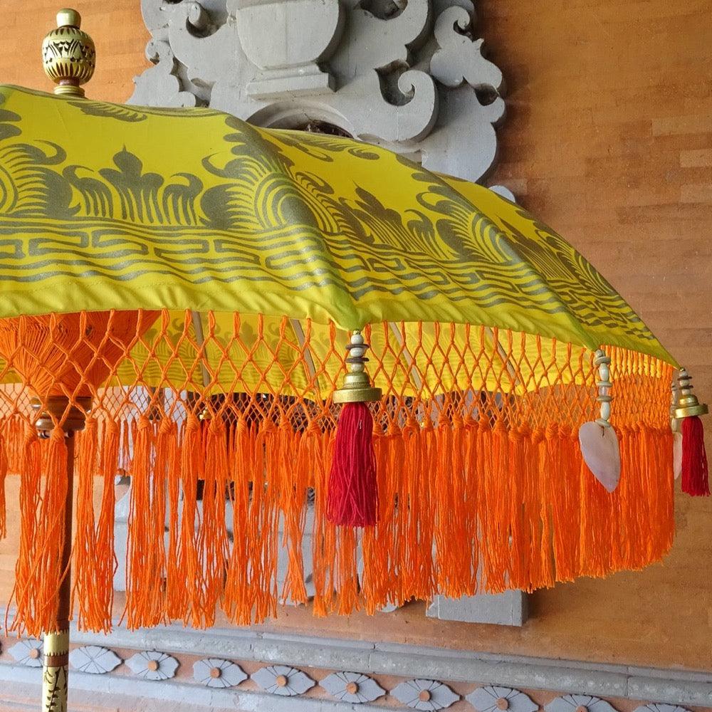 Luxury Arabella Parasol featuring golden patterns on yellow canvas with handcrafted wood and brass accents.