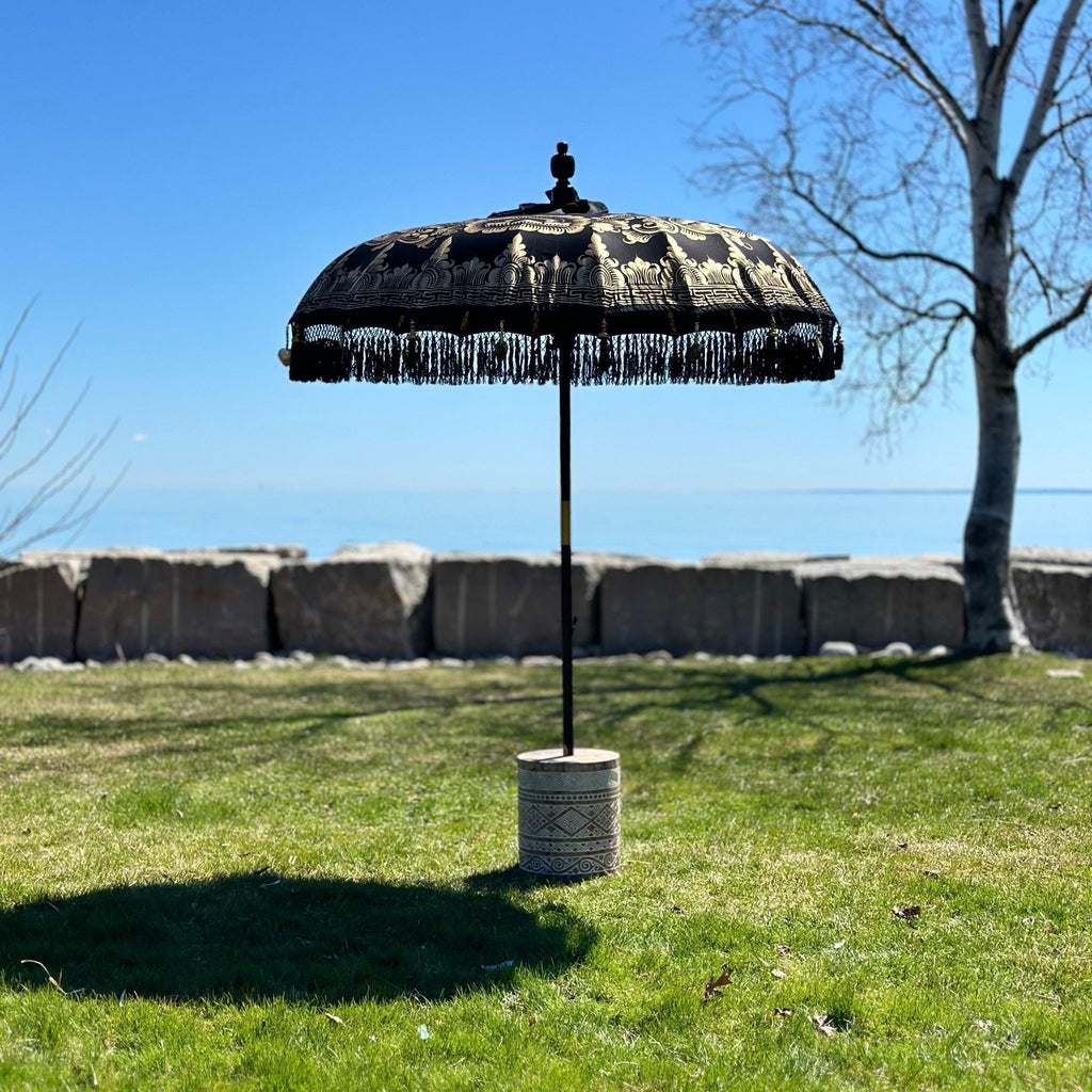 Elegant Carl Parasol in black and gold with handcrafted wooden pole and decorative black fringe.
