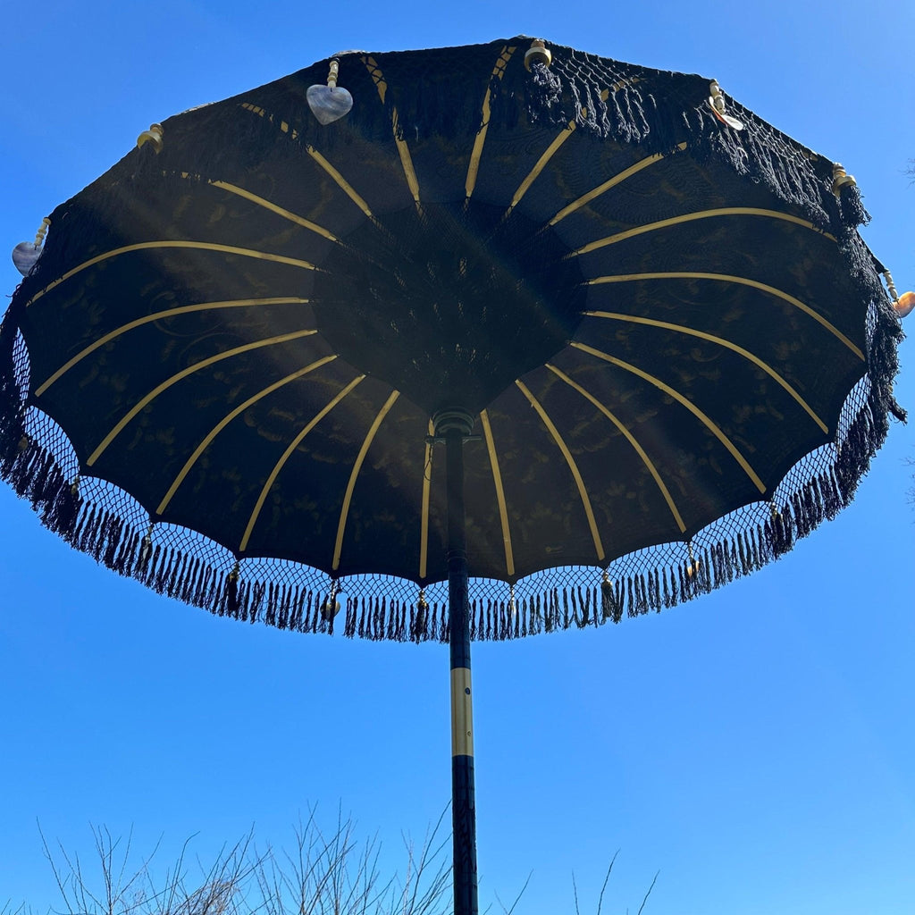 Hand-carved durian wood pole of the Carl Parasol with polished brass accents for a premium finish.