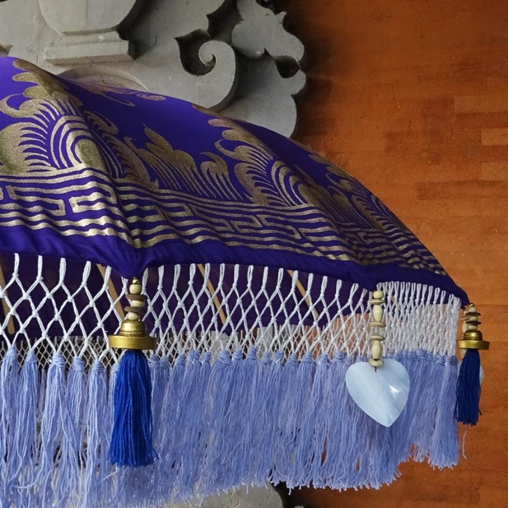 Close-up of Claudia Parasol’s intricate gold patterns and handcrafted lilac fringe with blue tassels.