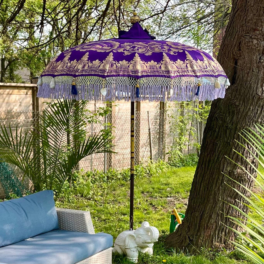 Full view of Claudia Parasol in a garden, showcasing its vibrant purple canopy and lilac fringe.