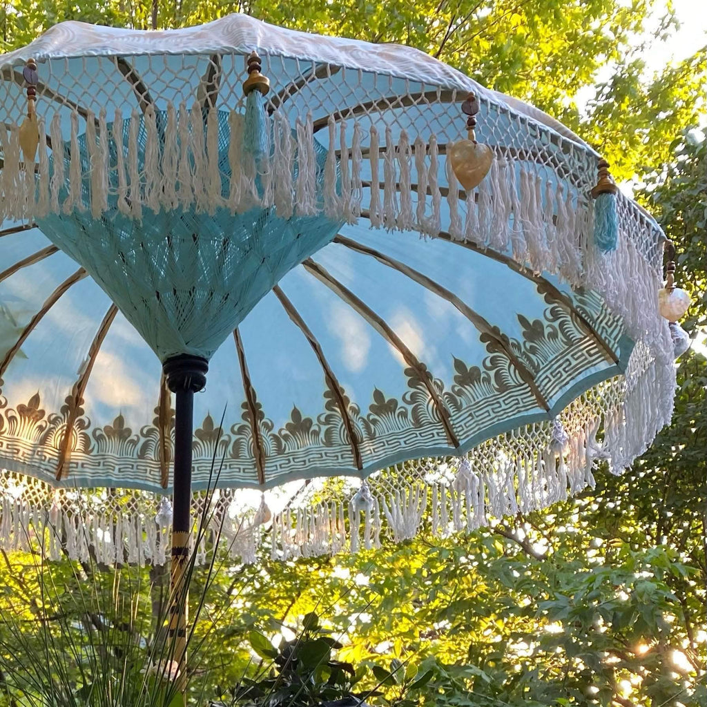 Detailed gold artwork on the Baby Blue Parasol, featuring handcrafted wooden elements and delicate blue tassels.